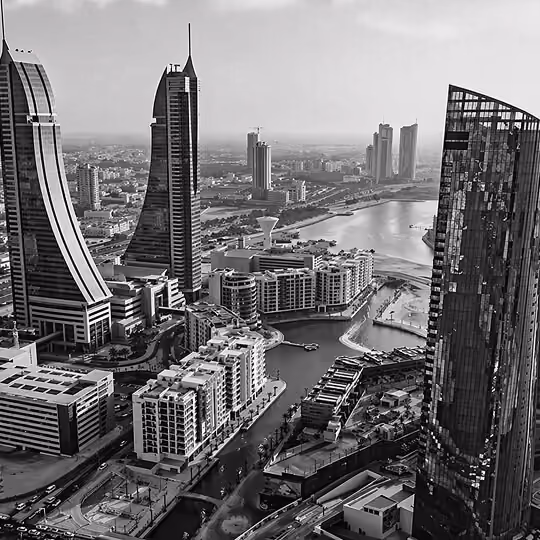 Black and white view of Manama skyline with modern skyscrapers and a busy highway in Bahrain.