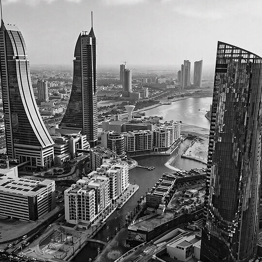 Black and white view of Manama skyline with modern skyscrapers and a busy highway in Bahrain.
