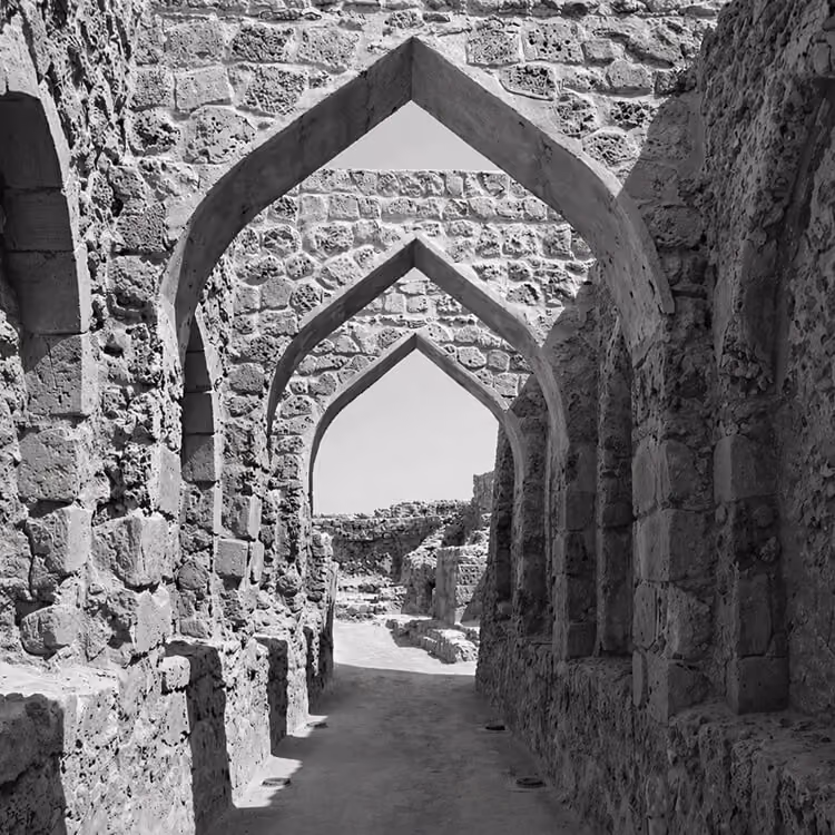 Black and white image of historic stone archways and pathways at Bahrain Fort in Manama.