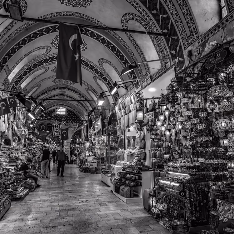 Black and white image of the Grand Bazaar interior with ornate arches and market stalls.