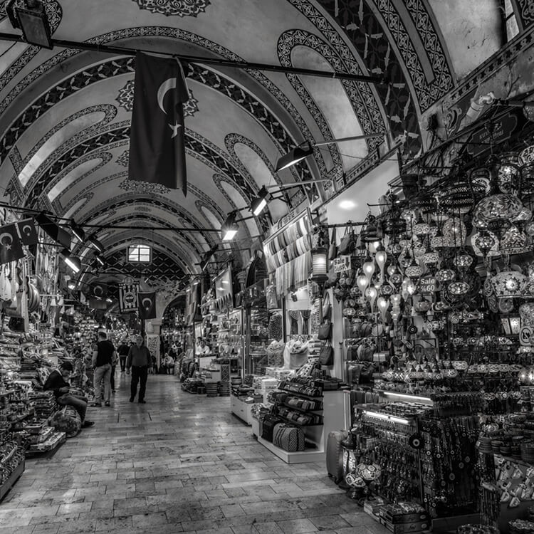 Black and white image of the Grand Bazaar interior with ornate arches and market stalls.
