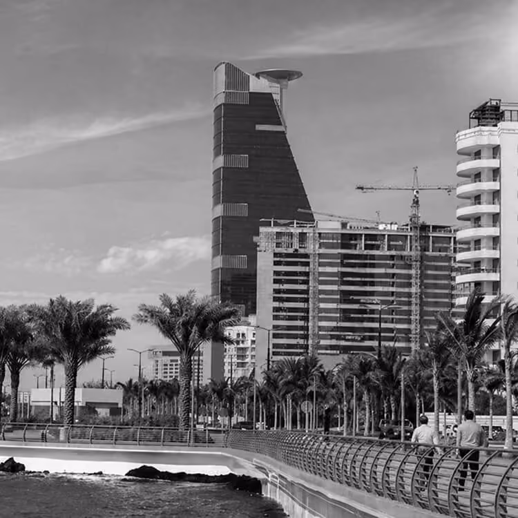 Jeddah Corniche skyline with modern waterfront buildings and palm-lined walkway along the Red Sea.