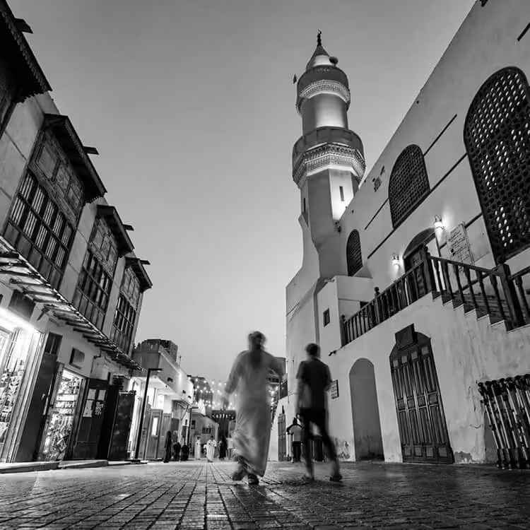 Evening street scene in Jeddah’s historic district with mosque minaret and traditional architecture.