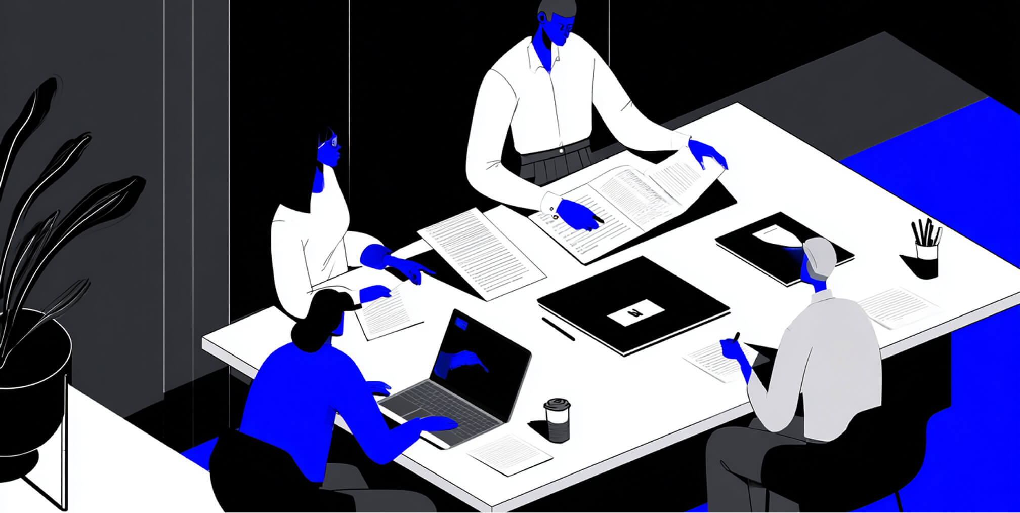 Team reviewing documents and working on laptops at a table, representing strategy and decision-making in selecting a logo design partner.