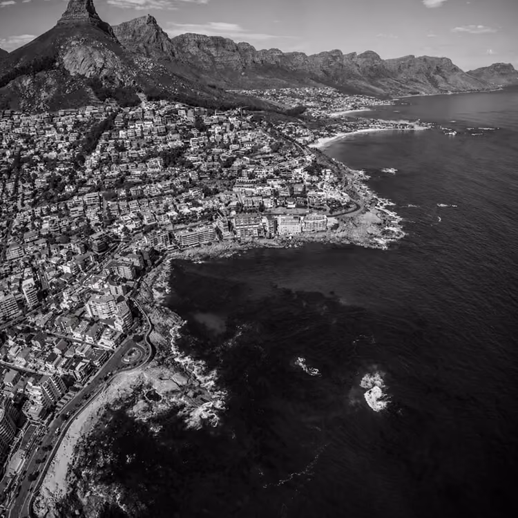 Aerial view of Cape Town coastline with dense hillside homes and ocean along the Atlantic coast.