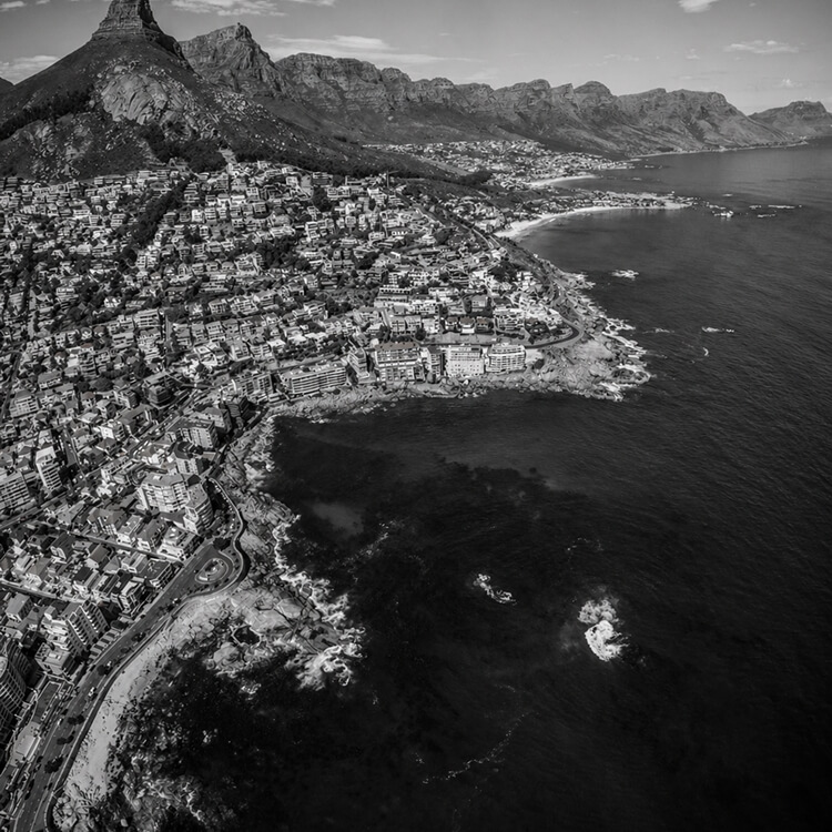 Aerial view of Cape Town coastline with dense hillside homes and ocean along the Atlantic coast.