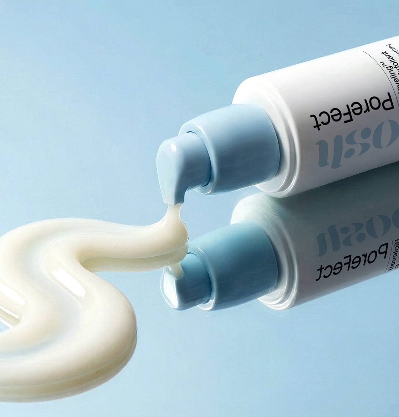 Close-up of Soloosh Porefect bottle dispensing cream onto a reflective surface with soft blue background.