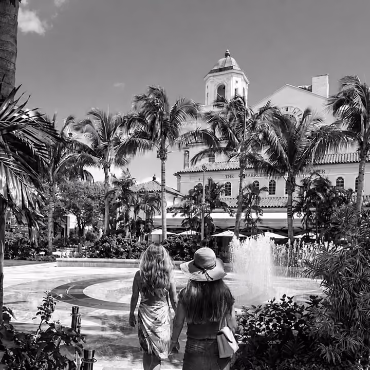 Luxury Florida resort courtyard with palm trees, fountain, and tropical architecture.