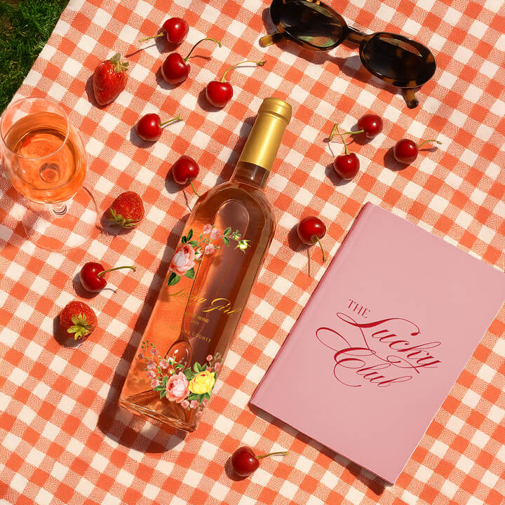 Rosé wine bottle with cherries, strawberries, sunglasses, and picnic-themed branding layout.