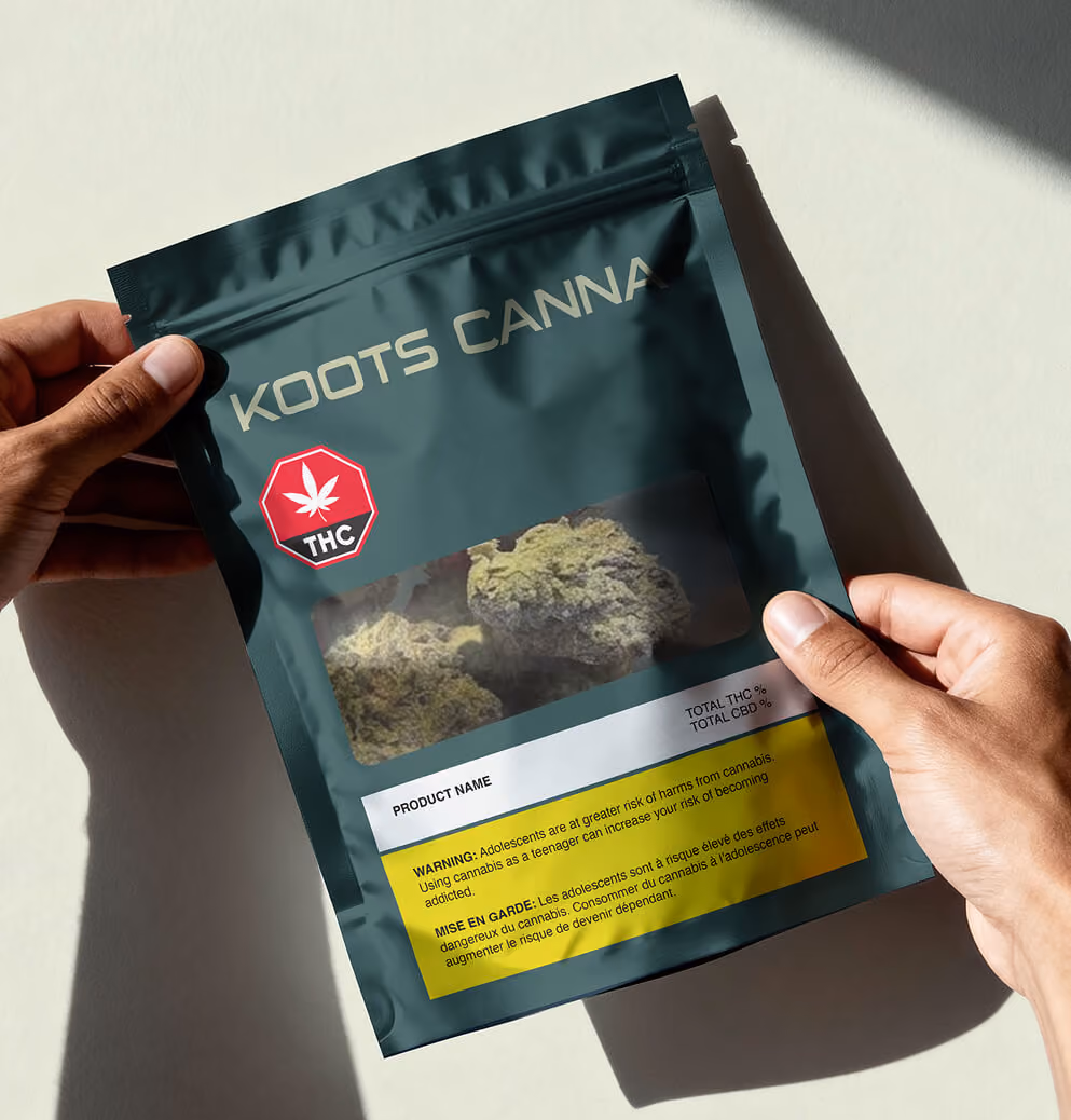 Hands holding Koots Canna cannabis product pouch with visible flower window and branded packaging design.