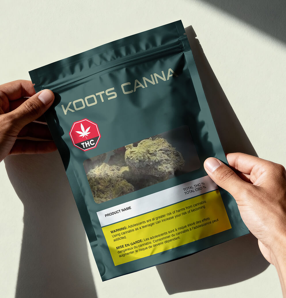 Hands holding Koots Canna cannabis product pouch with visible flower window and branded packaging design.