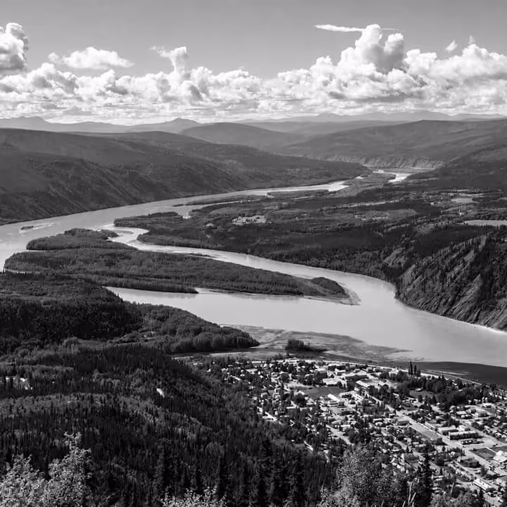 Sweeping aerial view of Yukon river valley winding through forests and mountain landscapes.