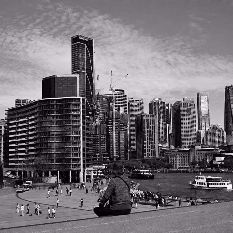 Sydney waterfront skyline with modern high-rise buildings, ferries, and public promenade.