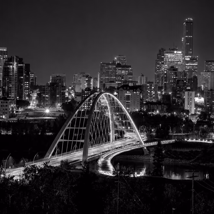 Nighttime view of Edmonton’s Walterdale Bridge illuminated against the city skyline.