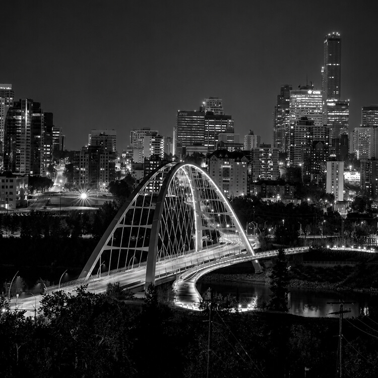 Nighttime view of Edmonton’s Walterdale Bridge illuminated against the city skyline.