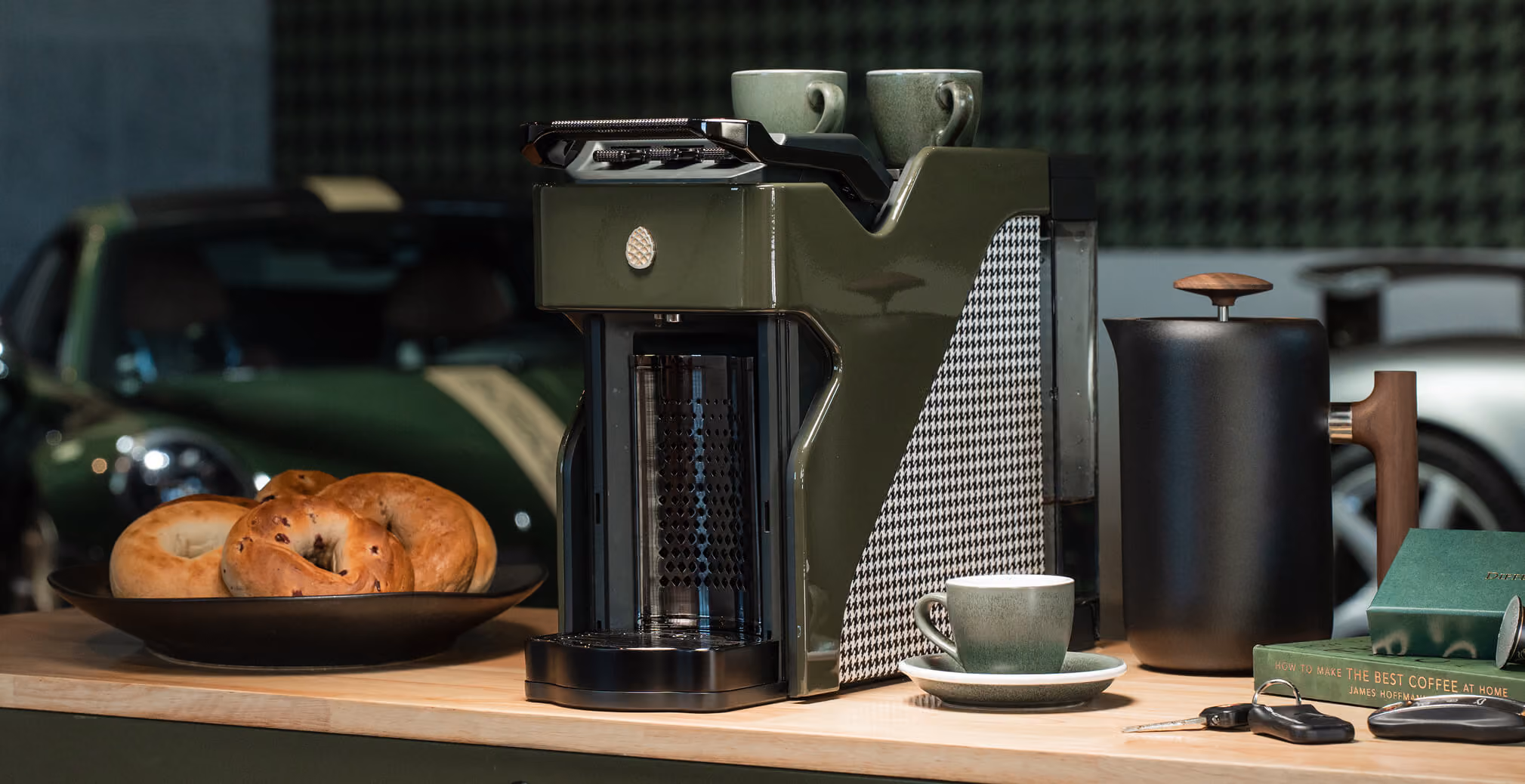 Premium Milton Coffee machine displayed on a wooden countertop with coffee cups, pastries, and luxury accessories in a sophisticated hospitality-inspired setting.