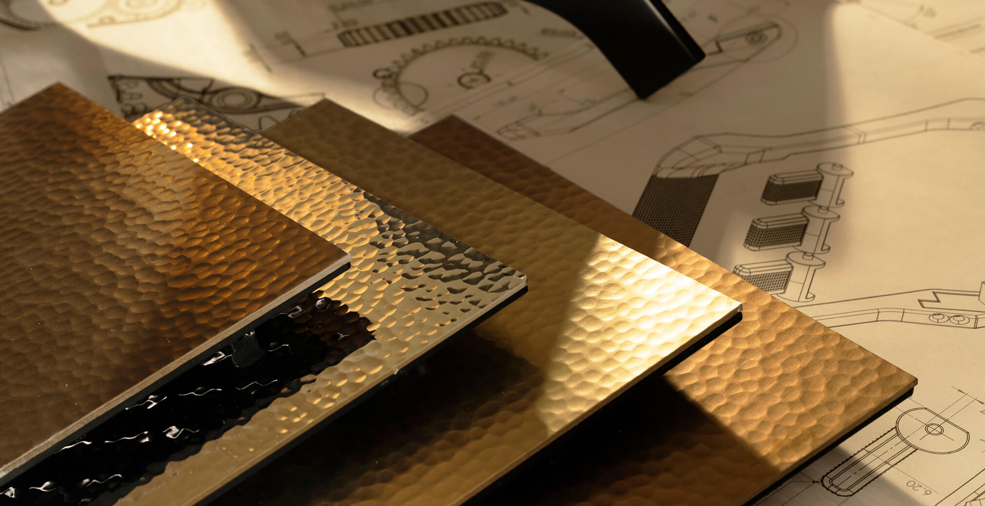 Collection of textured metallic material samples displayed over product engineering drawings, illustrating the design and development process behind the Milton Coffee machine.