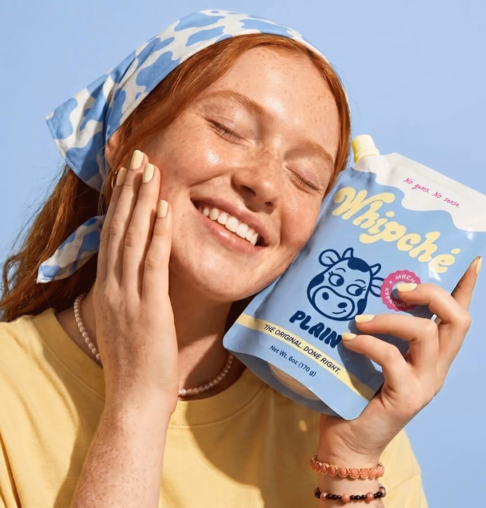 Consumer smiling while holding a pouch of Whipché plain cream cheese, showcasing brand affinity, packaging design, and lifestyle-focused marketing imagery.