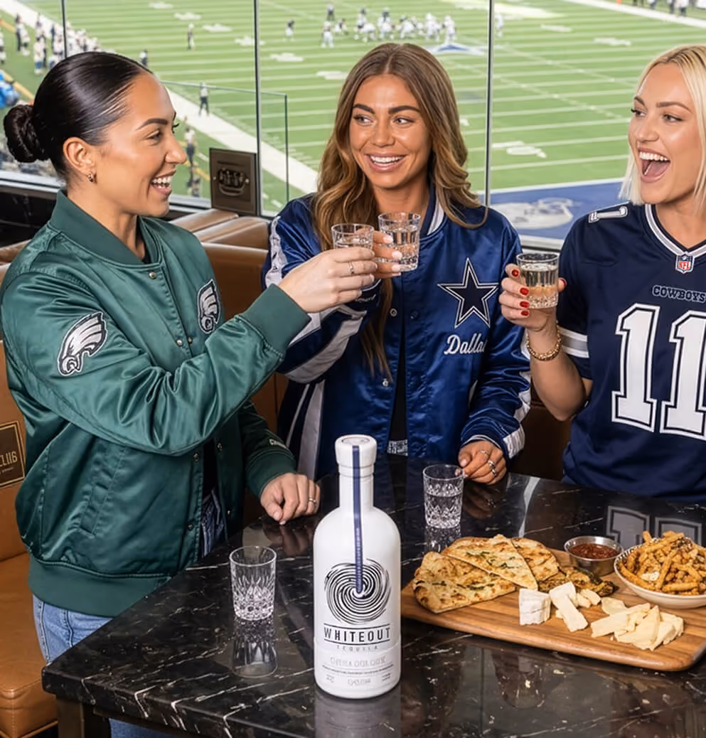 Group of sports fans enjoying tequila shots in a stadium suite with Whiteout Tequila prominently featured, showcasing lifestyle marketing and brand engagement.