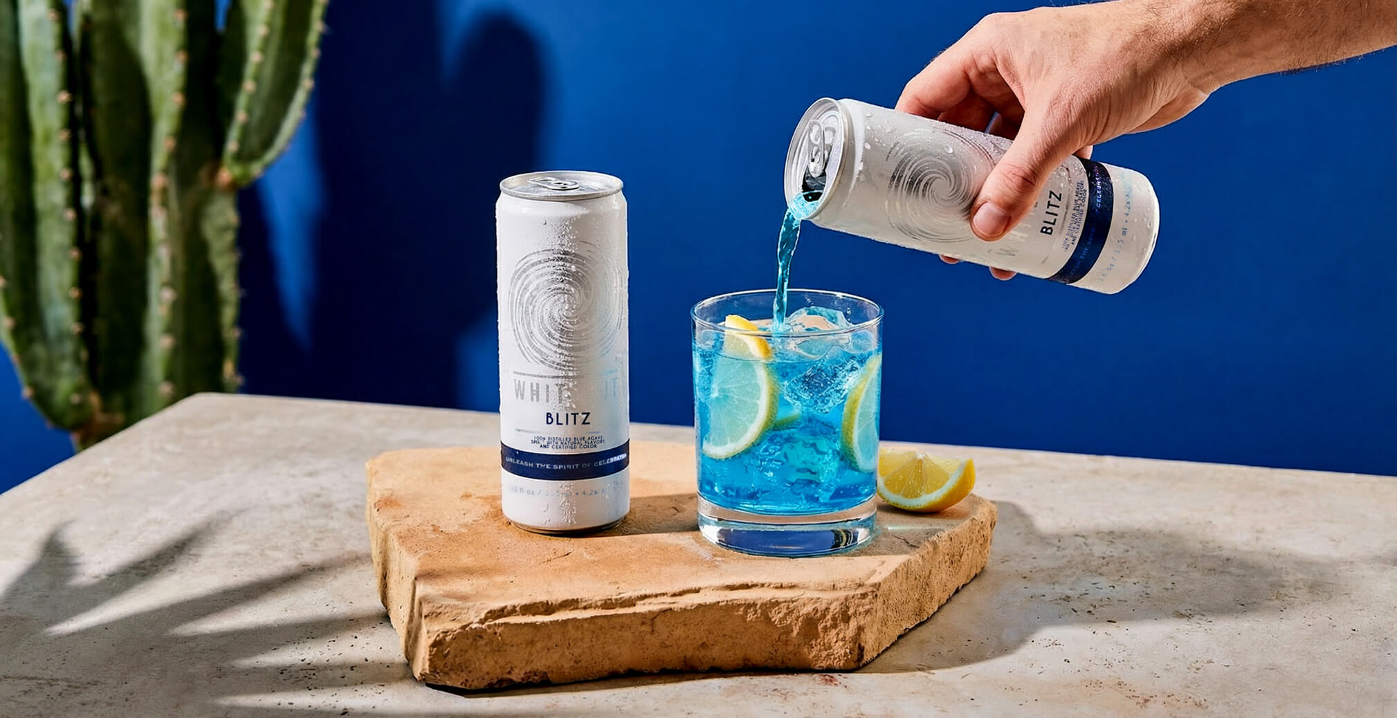 Blue Whiteout Blitz cocktail being poured over ice with fresh citrus, demonstrating product versatility and premium ready-to-drink positioning.