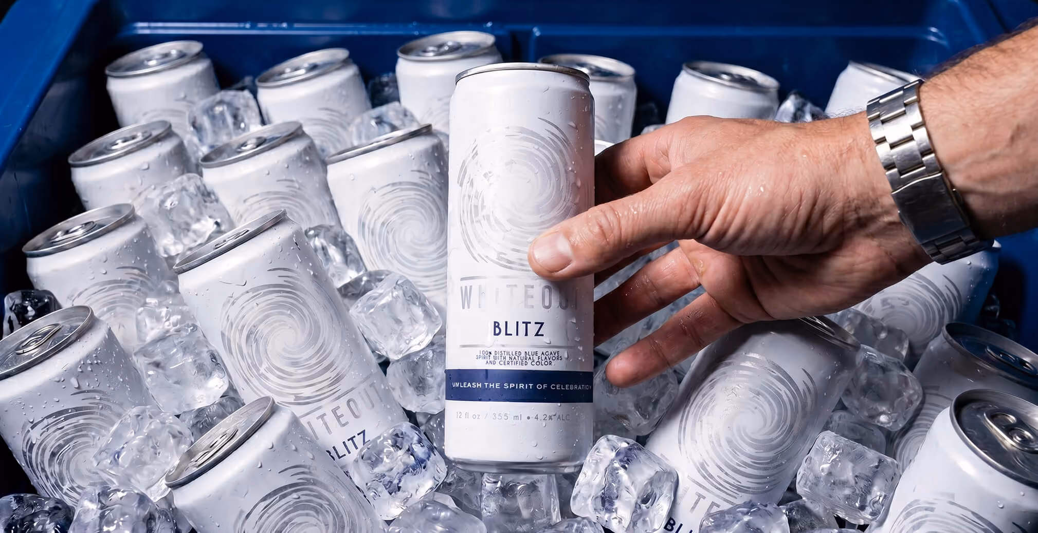Hand selecting a chilled Whiteout Blitz can from an ice-filled cooler, emphasizing refreshment, convenience, and consumer appeal.