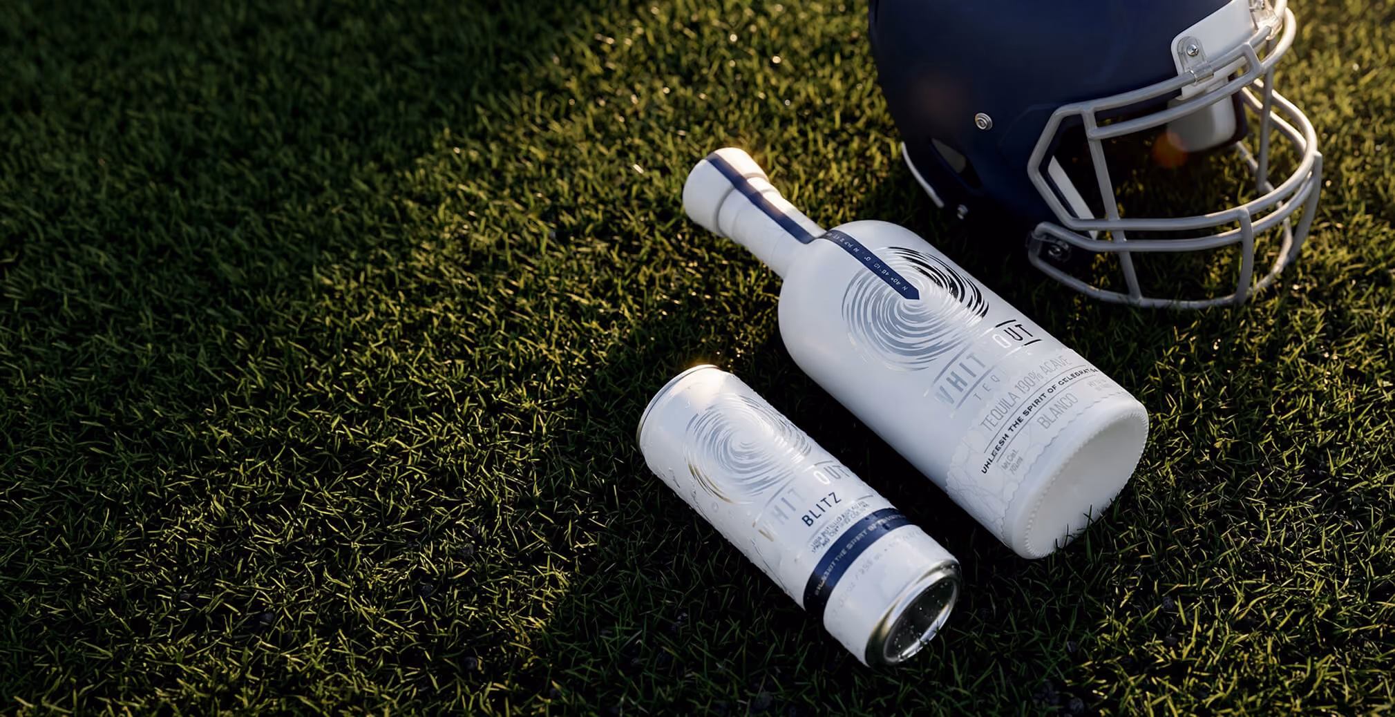 Whiteout Tequila bottle and canned cocktail displayed beside a football helmet on turf, connecting the brand with sports culture and entertainment experiences.
