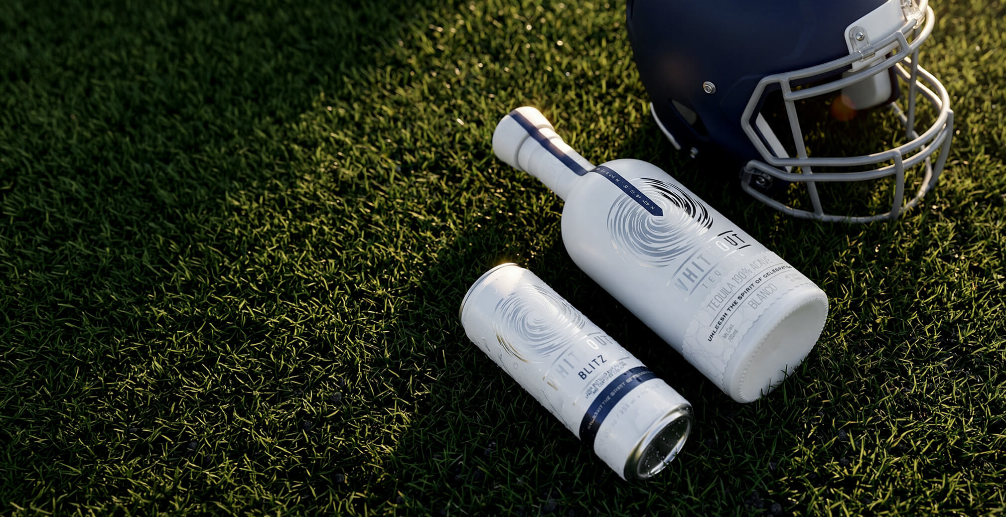 Whiteout Tequila bottle and canned cocktail displayed beside a football helmet on turf, connecting the brand with sports culture and entertainment experiences.