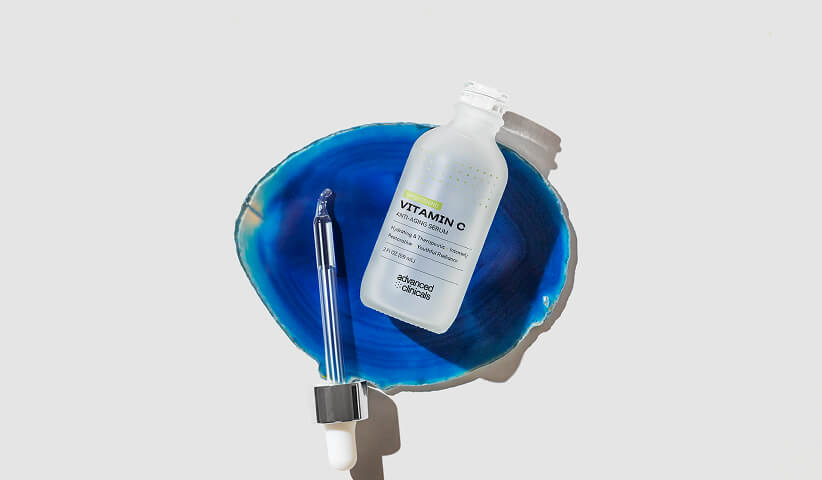 Vitamin C skincare serum presented with a dropper and vibrant blue backdrop, showcasing premium product packaging that communicates quality and product benefits.