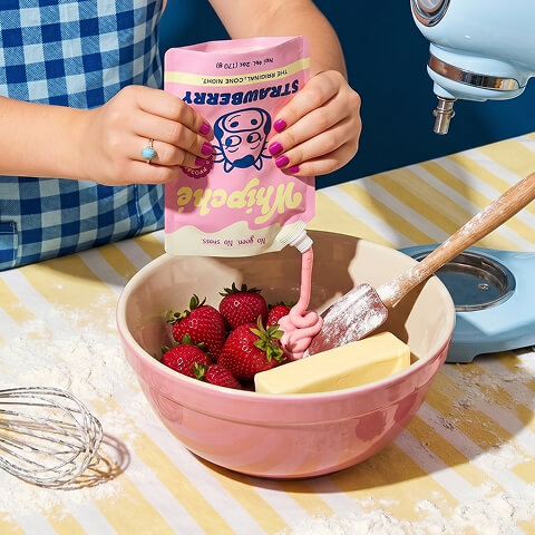 Consumer using branded strawberry whipped product packaging while baking, highlighting packaging design that integrates seamlessly into everyday product experiences.