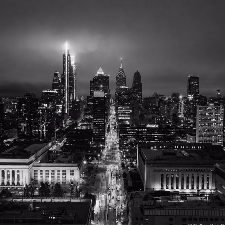 Philadelphia skyline illuminated at night along Broad Street with Center City skyscrapers.