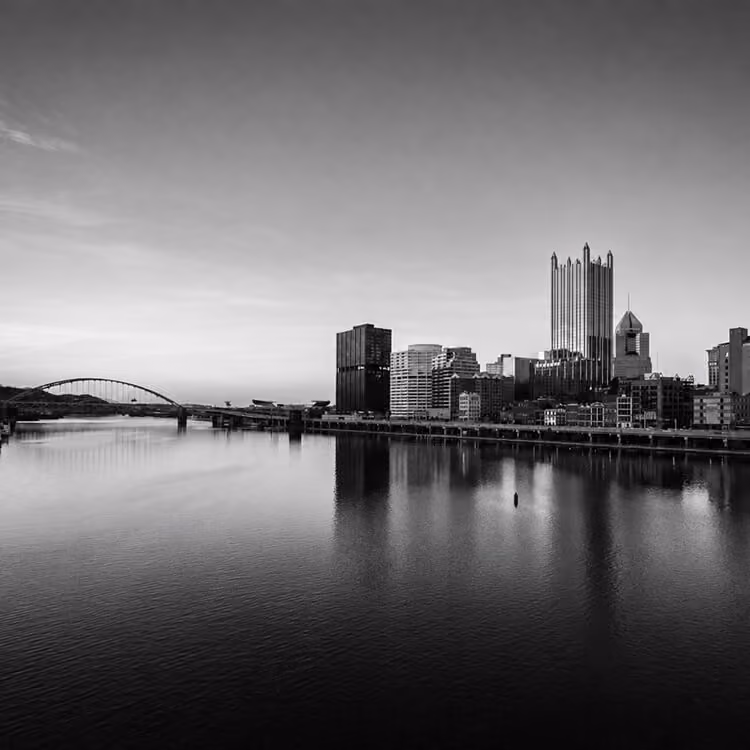 Pittsburgh skyline reflected along the Allegheny River with iconic downtown skyscrapers.