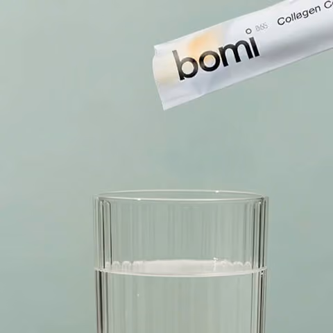 Collagen supplement powder being poured into a glass of water for daily consumption.