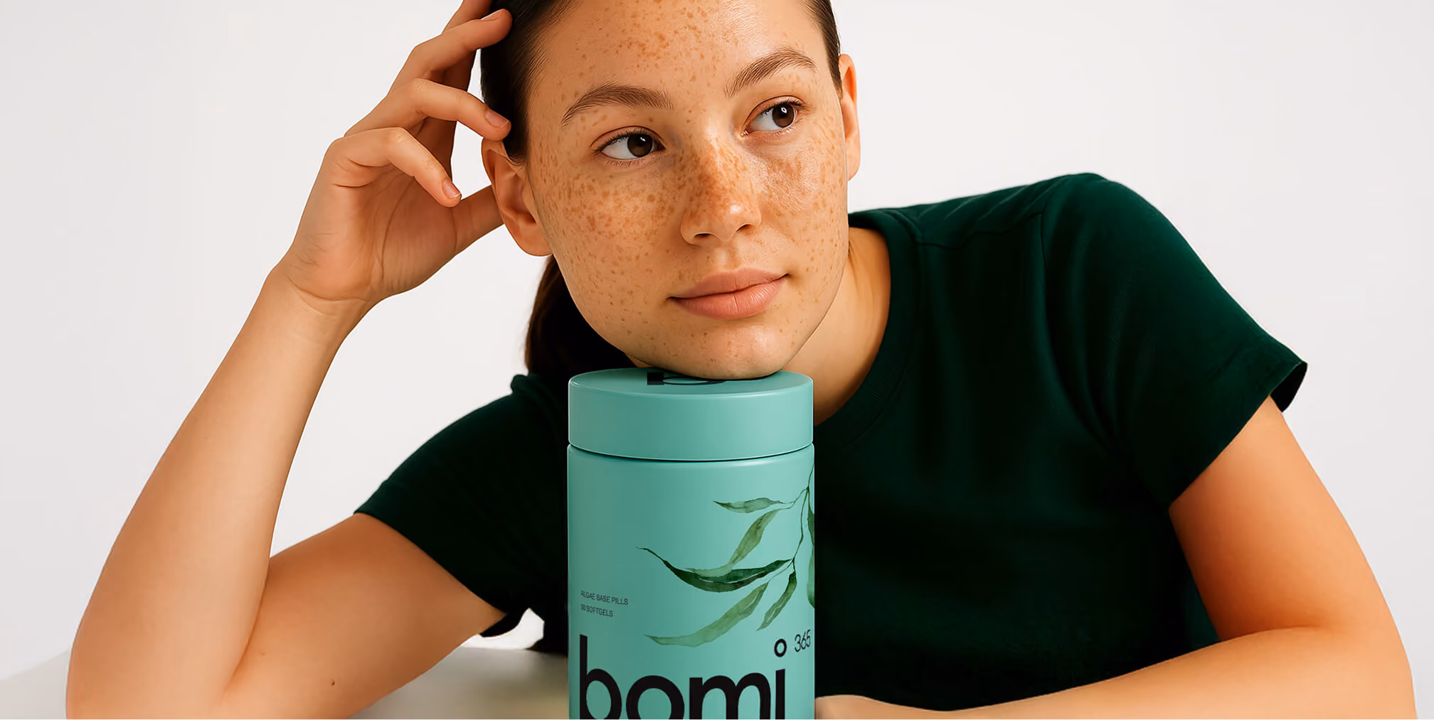 Lifestyle portrait featuring a wellness consumer with premium supplement packaging in a clean, modern setting.