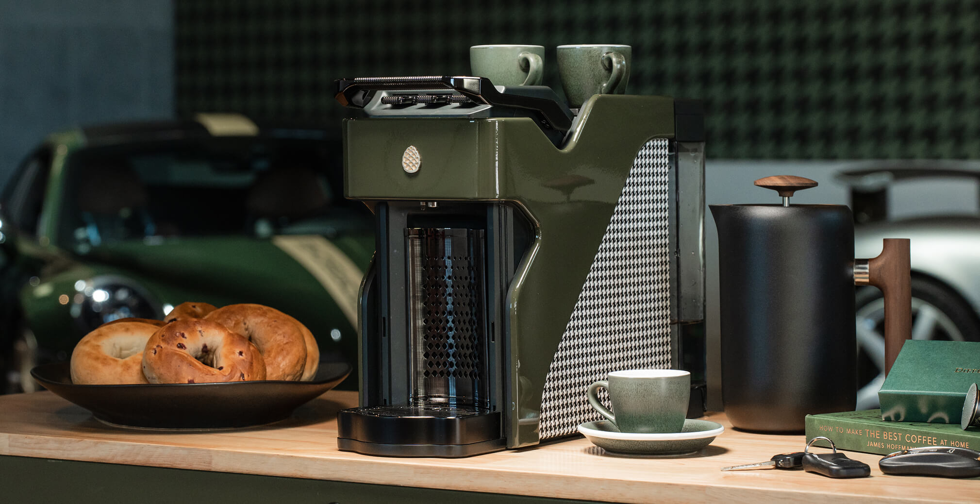 Premium Milton Coffee machine displayed on a wooden countertop with coffee cups, pastries, and luxury accessories in a sophisticated hospitality-inspired setting.