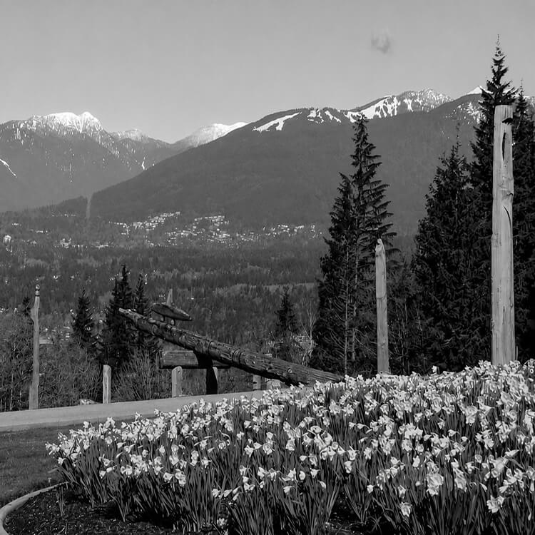 Mountain views from Burnaby Mountain Park with blooming spring flowers, Indigenous totem poles, and the North Shore Mountains in the background.