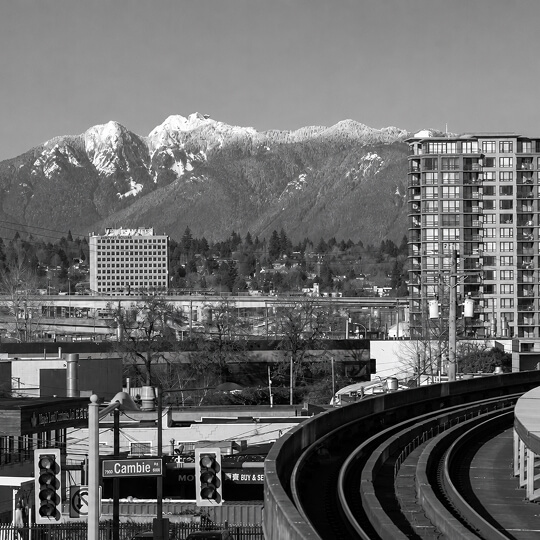 Richmond skyline with the Canada Line SkyTrain and the North Shore Mountains rising in the background.