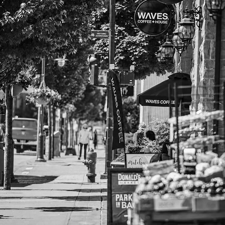 Sidewalk café scene in historic Downtown Coquitlam featuring local coffee shops, storefronts, and a vibrant pedestrian-friendly streetscape.