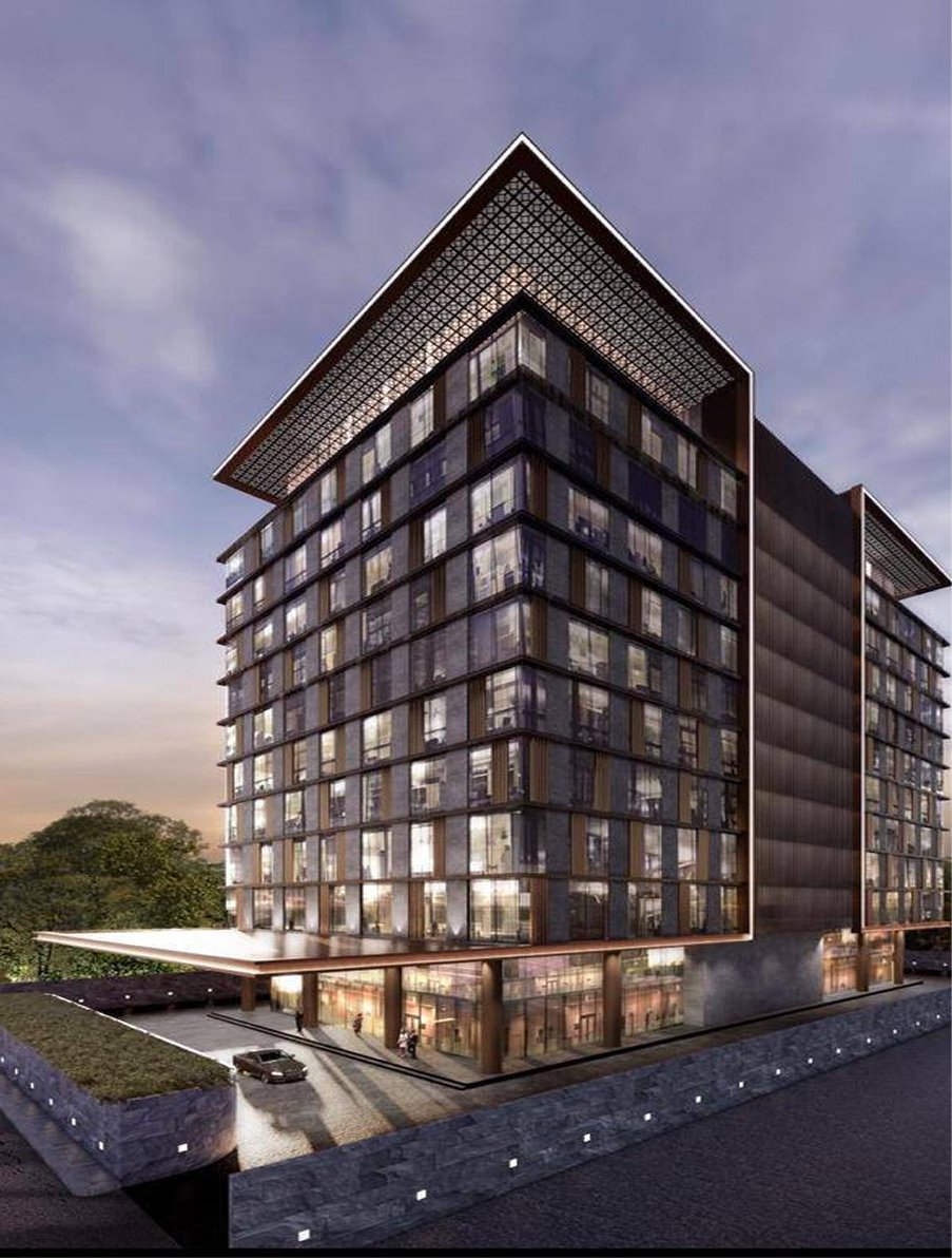 Modern multi-story glass office building with illuminated interior at dusk and a car parked at the entrance.
