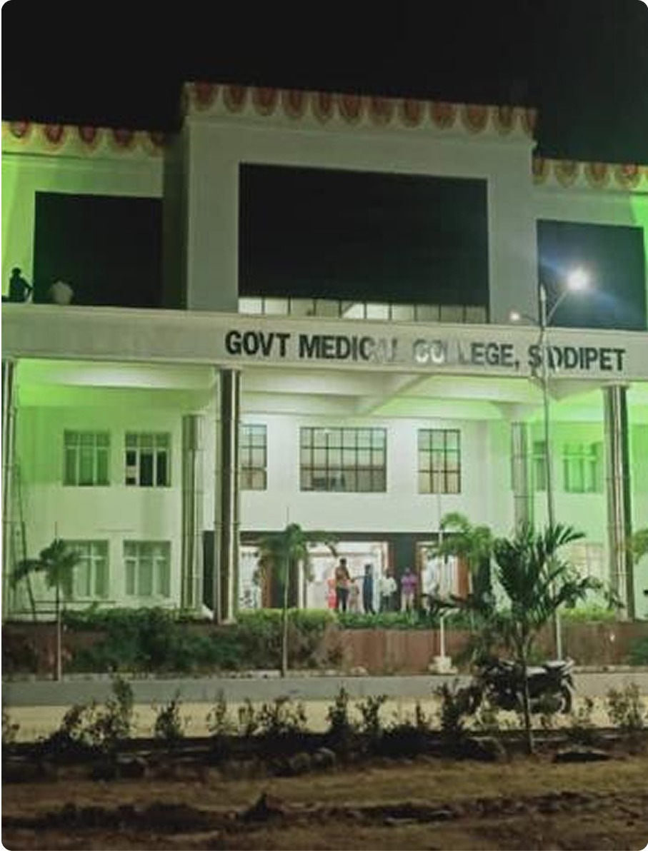 Night view of government medical college building with illuminated entrance and people standing outside.