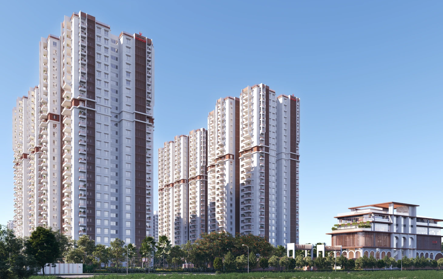 Modern residential high-rise buildings with balconies next to a multi-story clubhouse surrounded by trees under a clear blue sky.