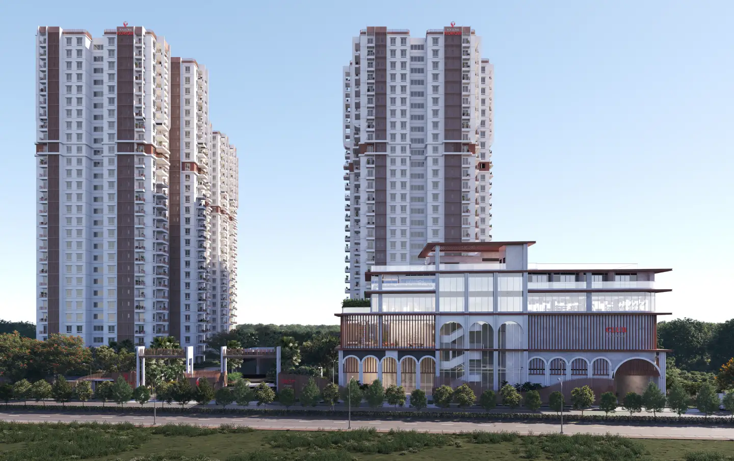 Modern high-rise residential towers with a glass-fronted clubhouse in front, surrounded by trees and a road.