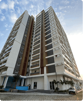 Low-angle view of a modern high-rise residential building with balconies against a partly cloudy sky.