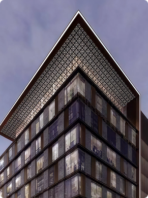 Modern glass building with a distinctive wide, patterned overhanging roof against a cloudy sky.