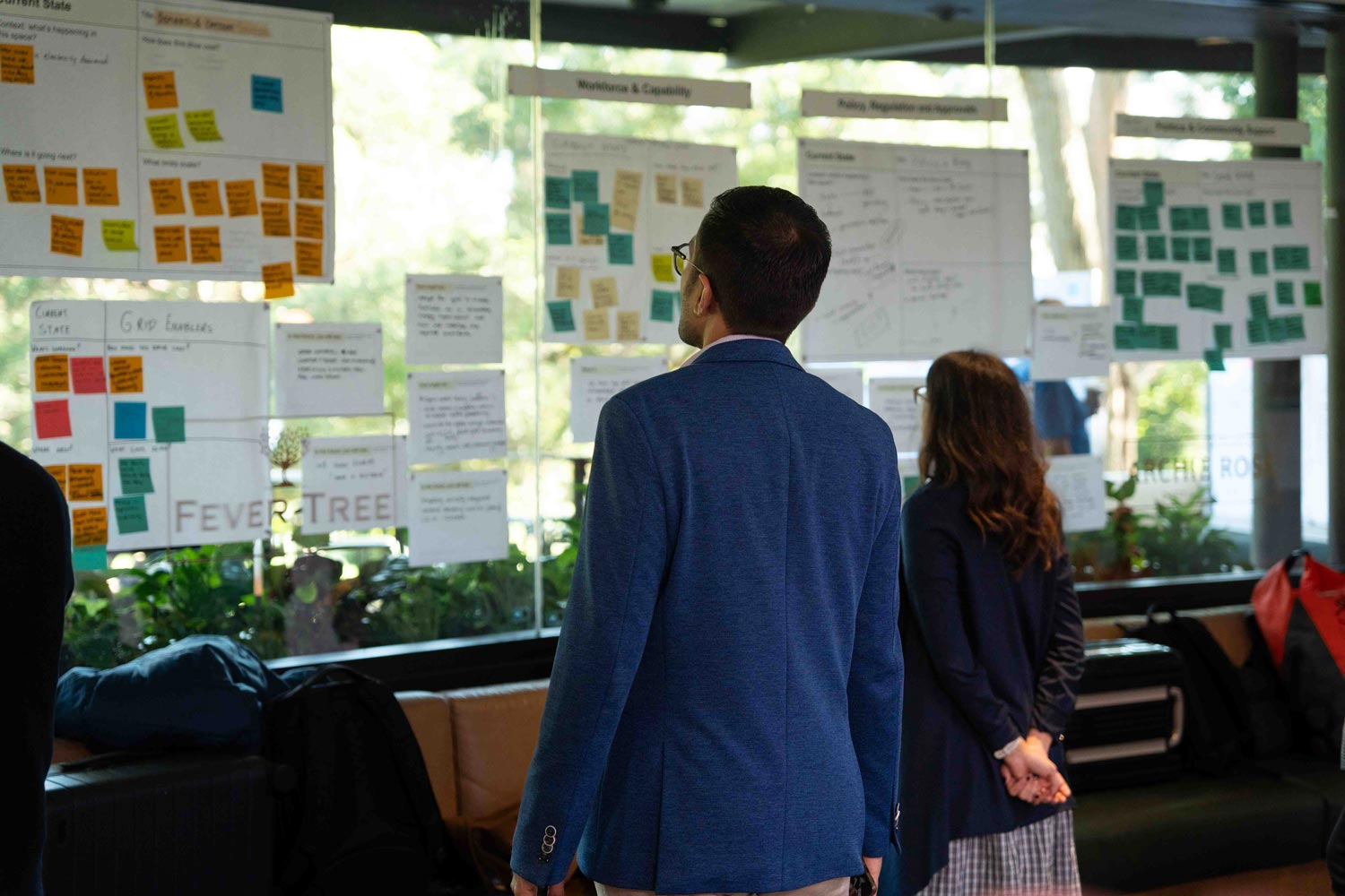 A man looking at a wall filled with post it notes and ideas from the Solar Challenge