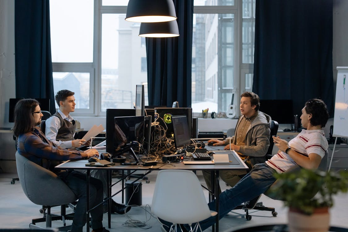 A diverse software development team collaborating in a modern office, working on multiple monitors during an AI risk management project.