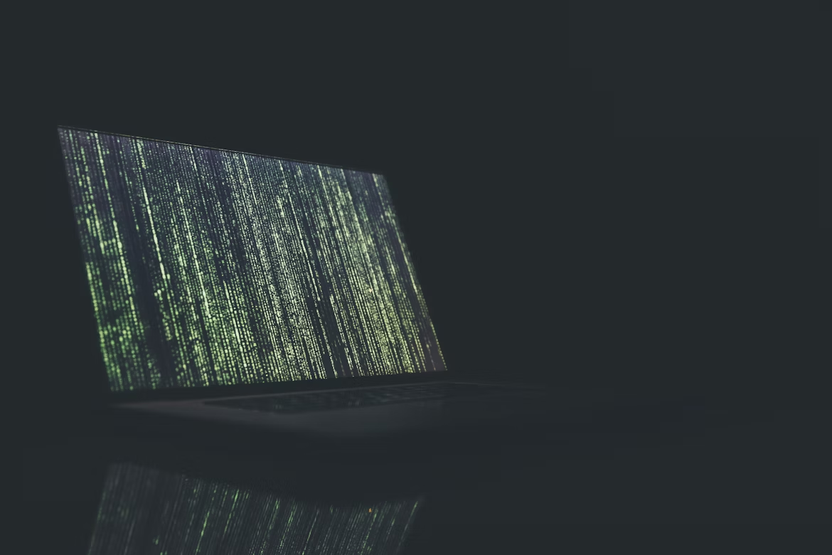 Close-up of a laptop displaying cascading green code, symbolizing AI algorithms, data analysis, and AI risk assessment