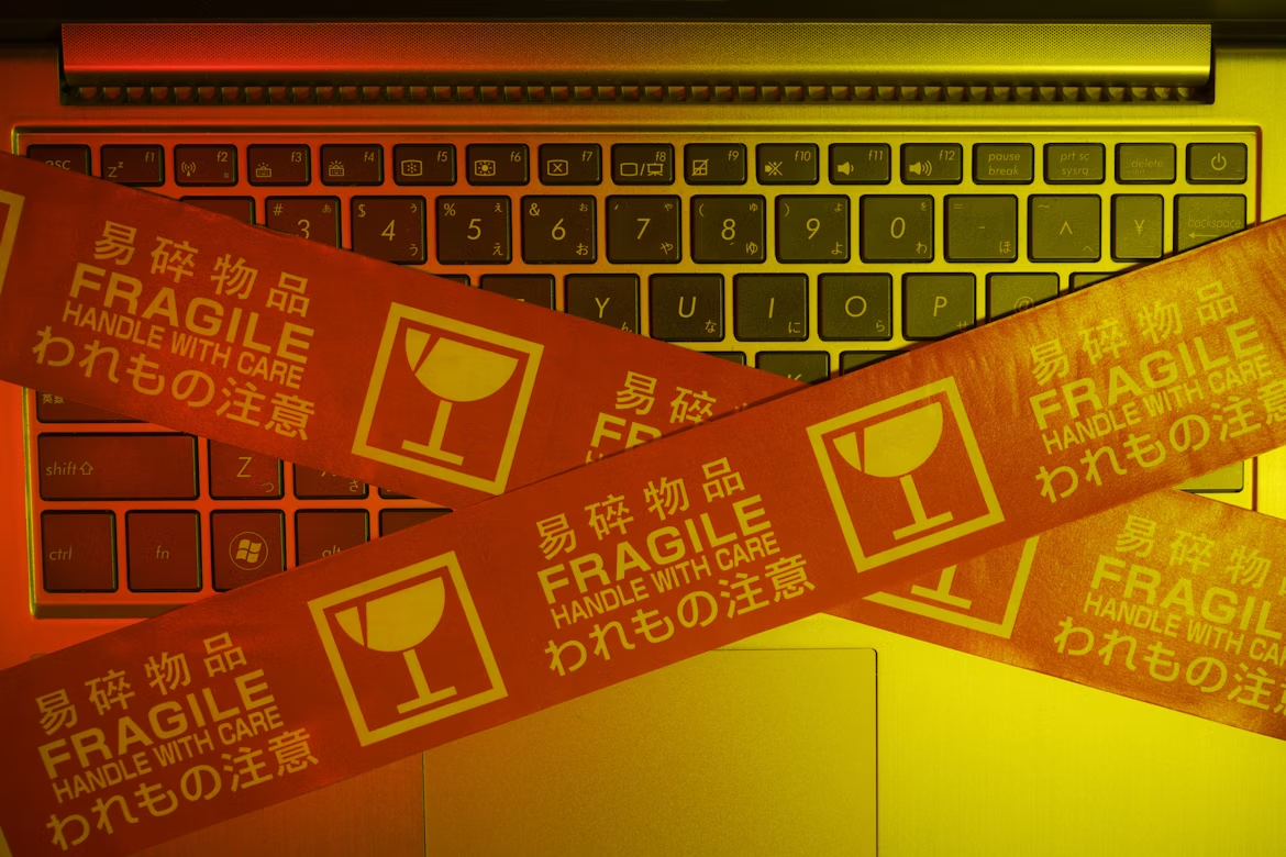 Laptop keyboard covered with “fragile” warning tape, symbolizing the vulnerabilities and risks associated with high-risk AI systems that require safeguards and responsible handling