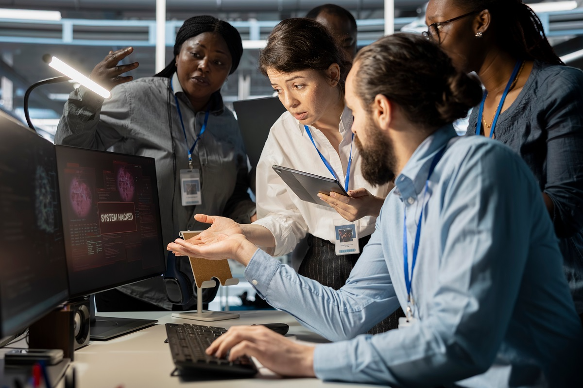 Cybersecurity team investigating a potential AI-related system breach on a computer displaying a hacked alert