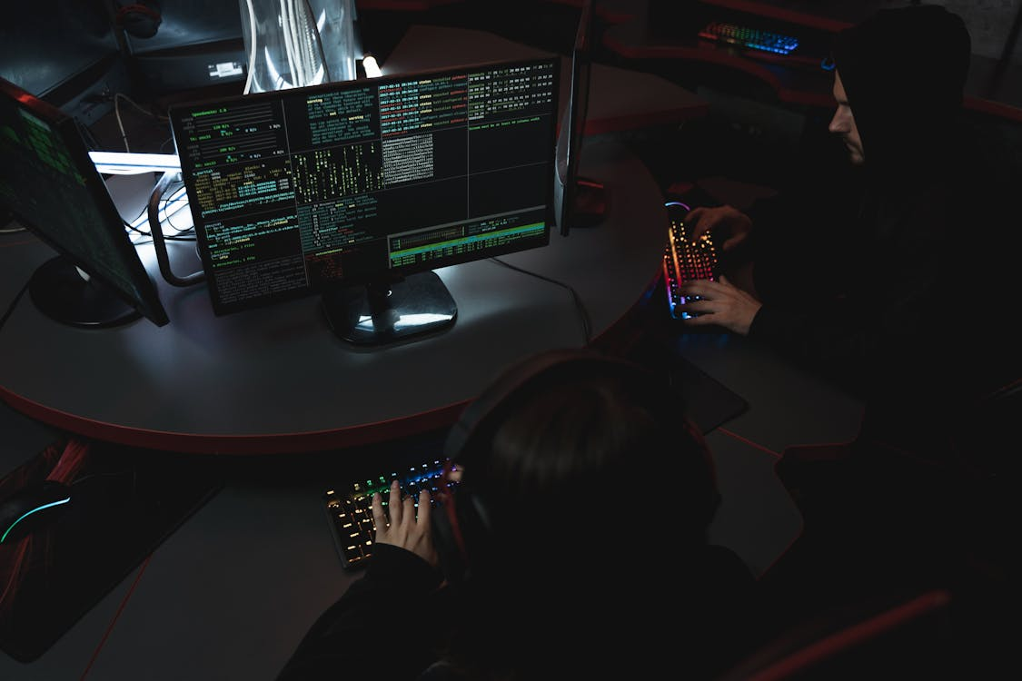 Cybersecurity professionals analyzing code and system logs on multiple monitors during an AI security testing or red teaming exercise