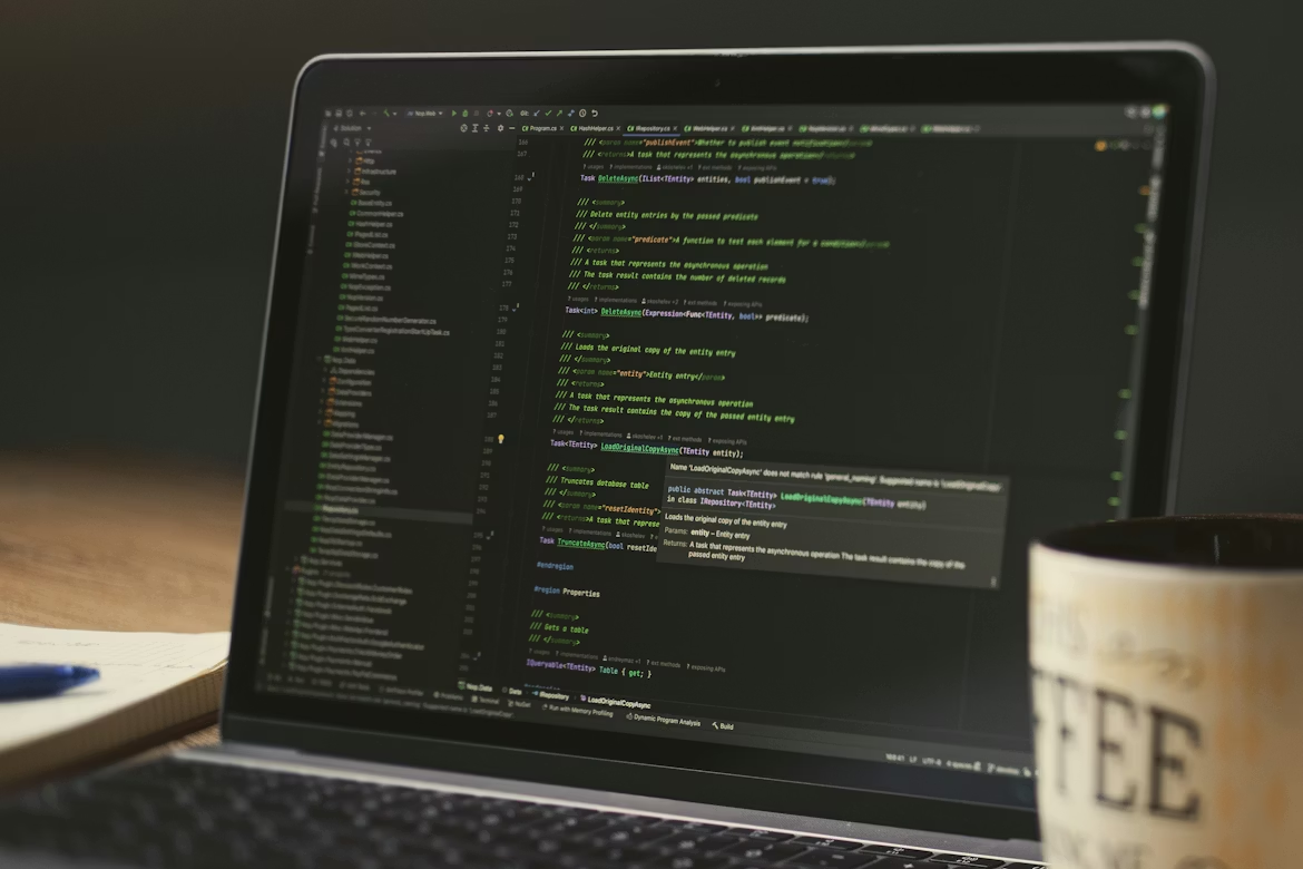 Laptop displaying programming code and software development environment, representing AI engineering, cybersecurity development, and secure application programming